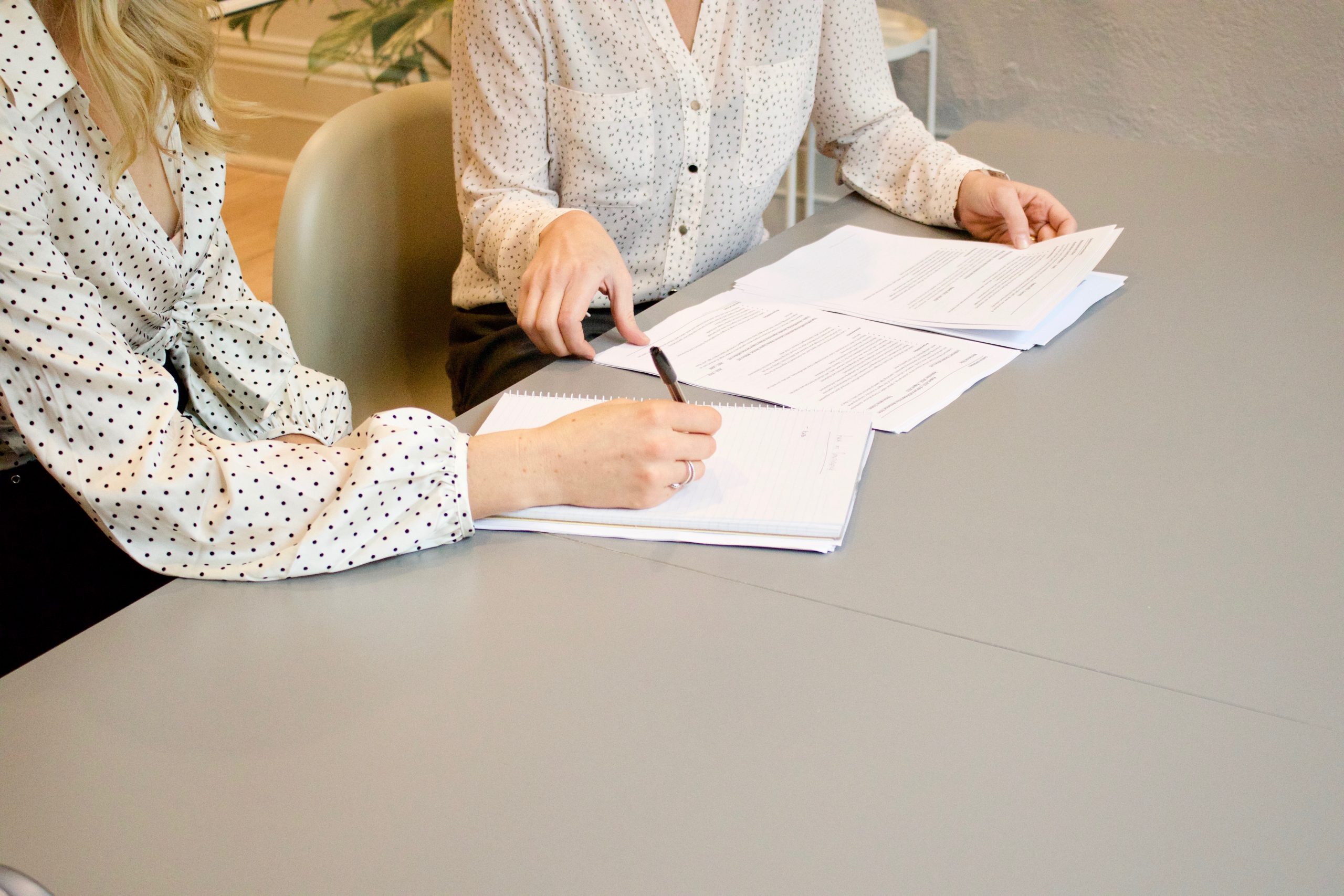 Mensen in overleg met papieren op bureau.