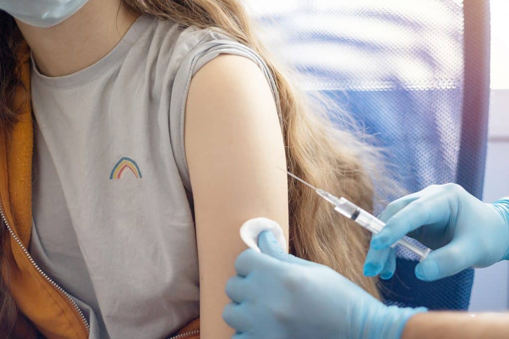 a doctor in gloves vaccinates a teenage girl
