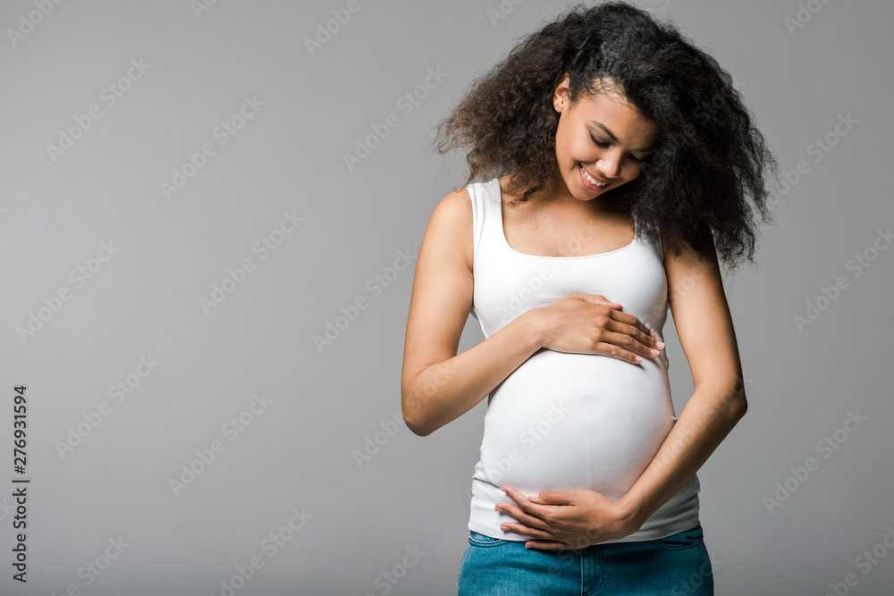 Zwangere jonge vrouw omarmt eigen buik.